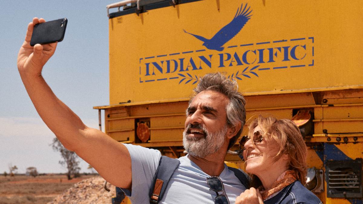 man taking selfie of himself and a woman in front of Indian Pacific train