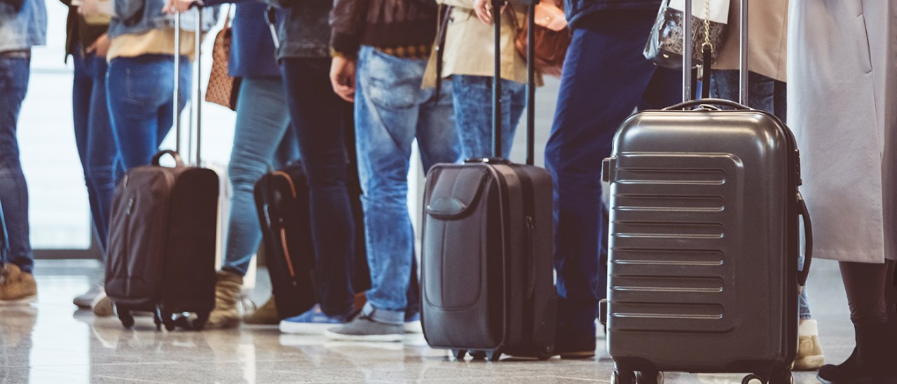 people lining up with bags to check in at airport
