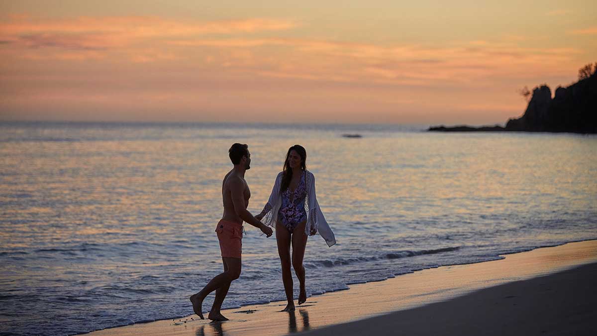 couple walking on Fijian beach at sunset
