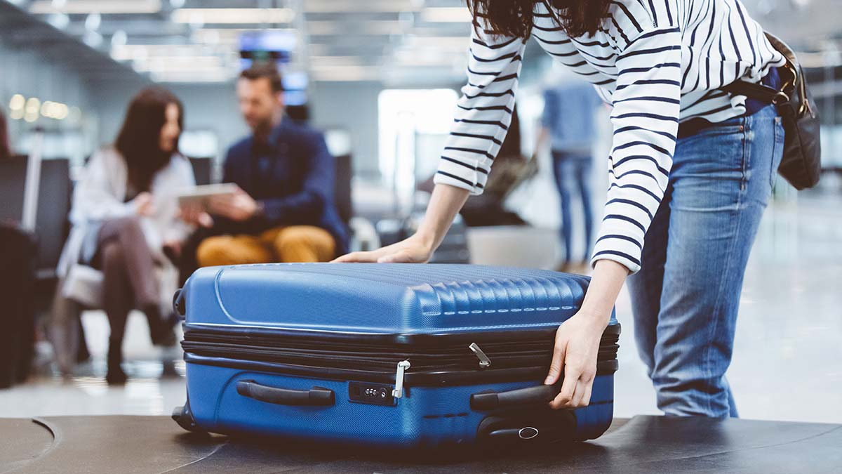 Woman picking up luggage from airport carousel