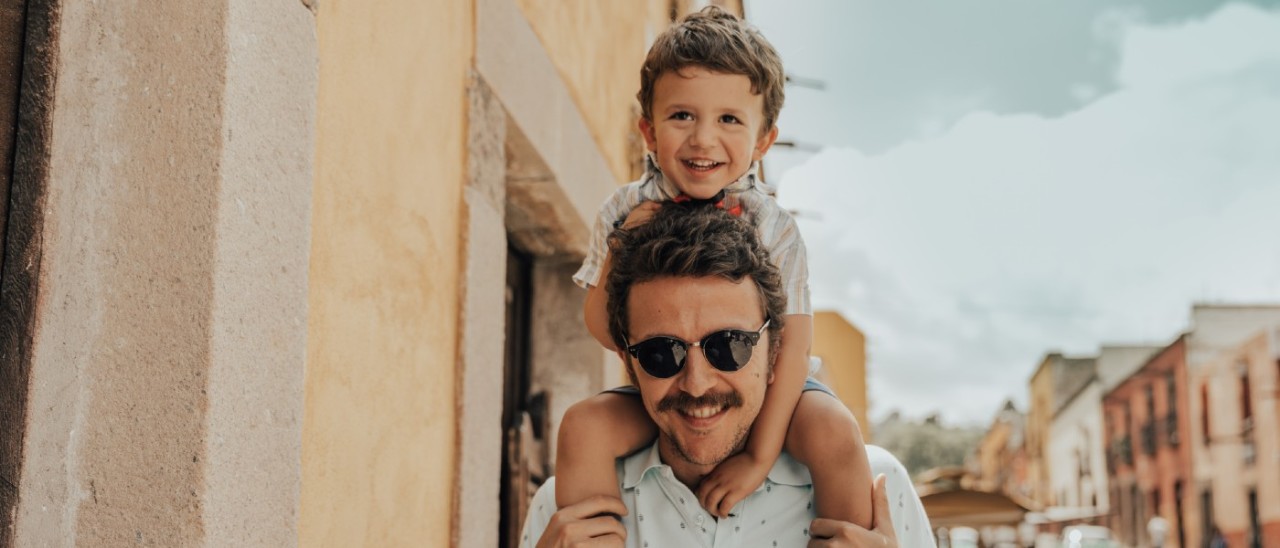 father holding son on his shoulders in overseas city