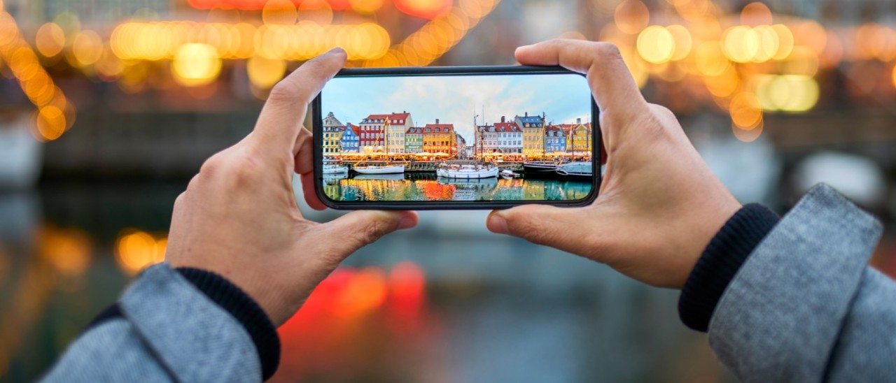 man taking a photo of Danish houses on his smartphone
