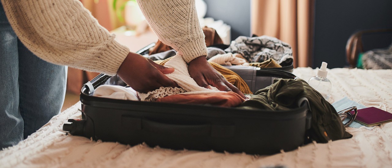 Woman packing suitcase on bed.