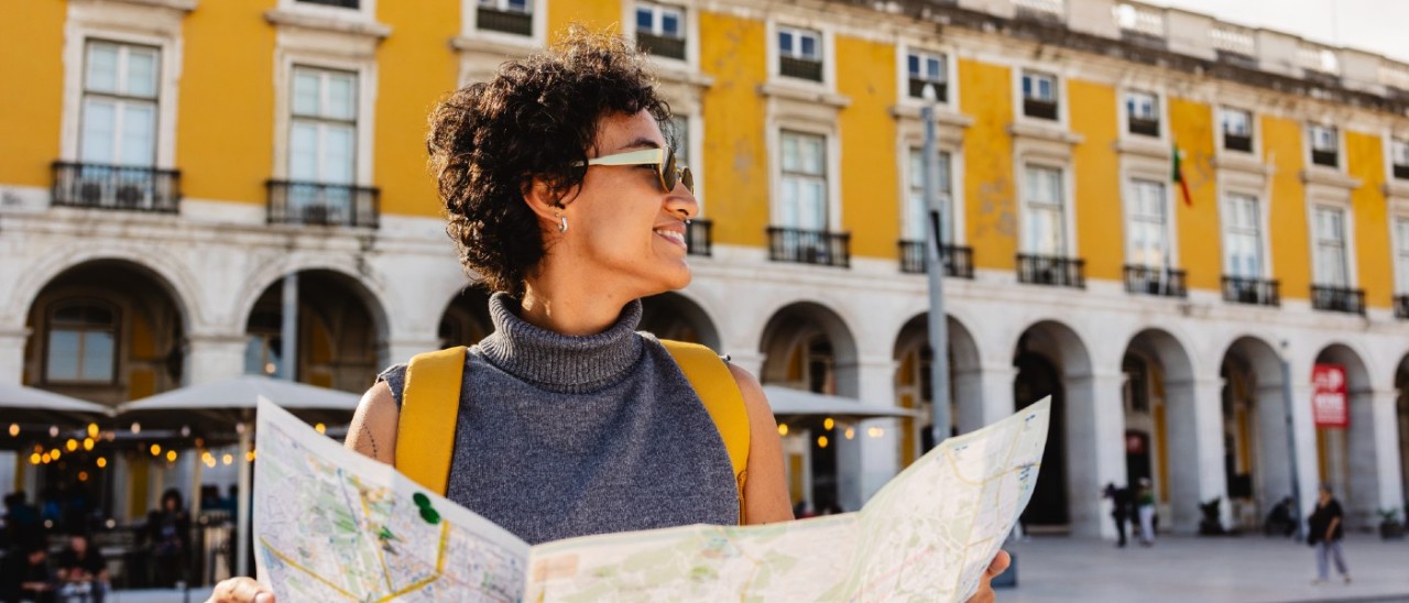 young woman smiling in sunglasses holding a map in Lisbon