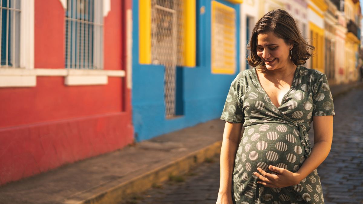 pregnant woman smiling and touching her belly in European street