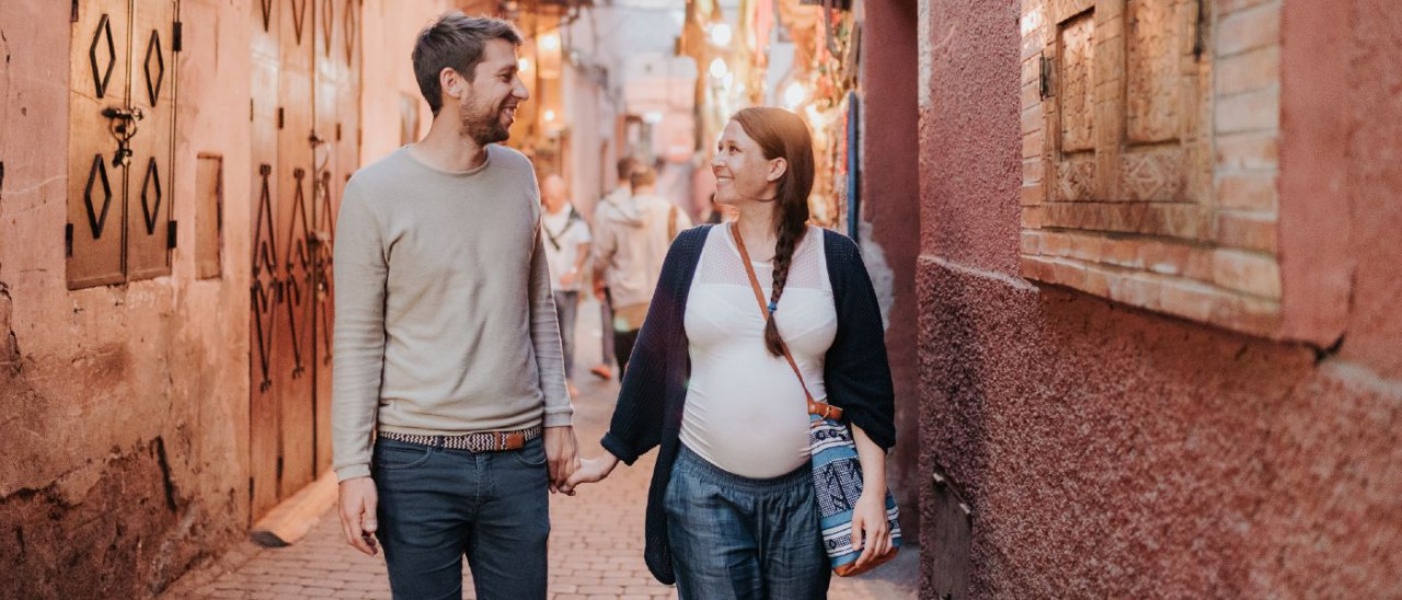 young man and pregnant woman holding hands while travelling