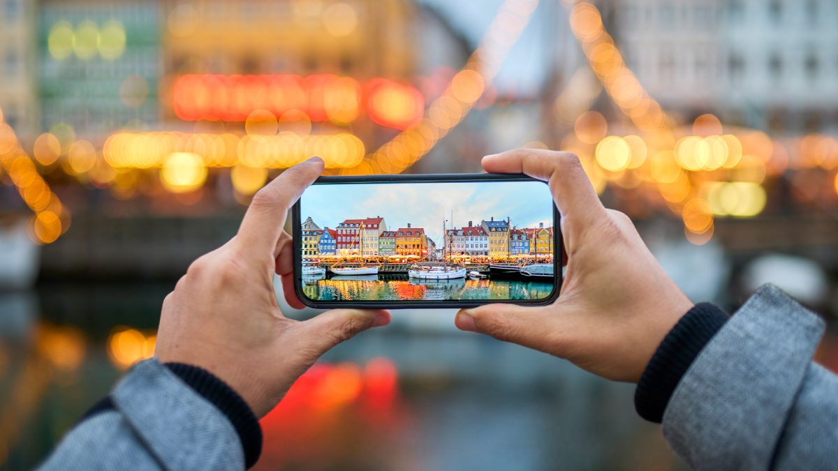 man taking a photo of Danish houses on his smartphone