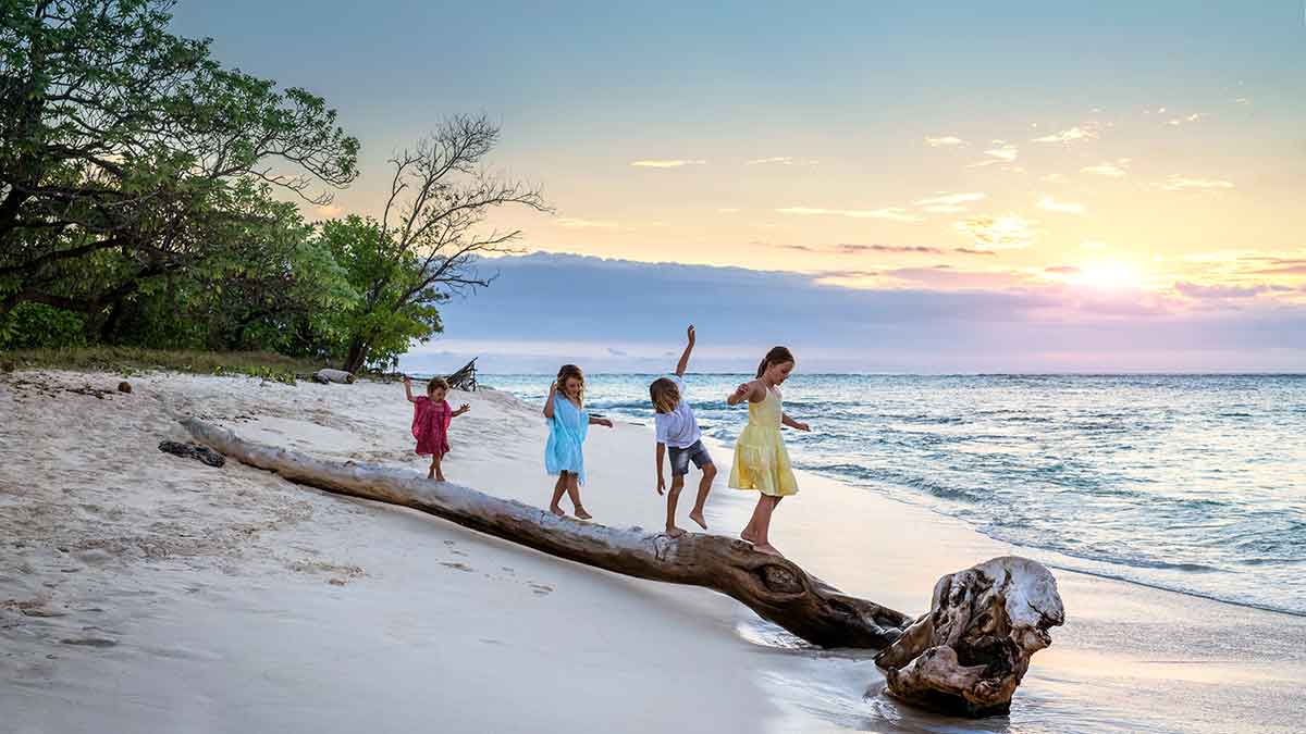 kids playing on a driftwood log by the ocean in Fiji