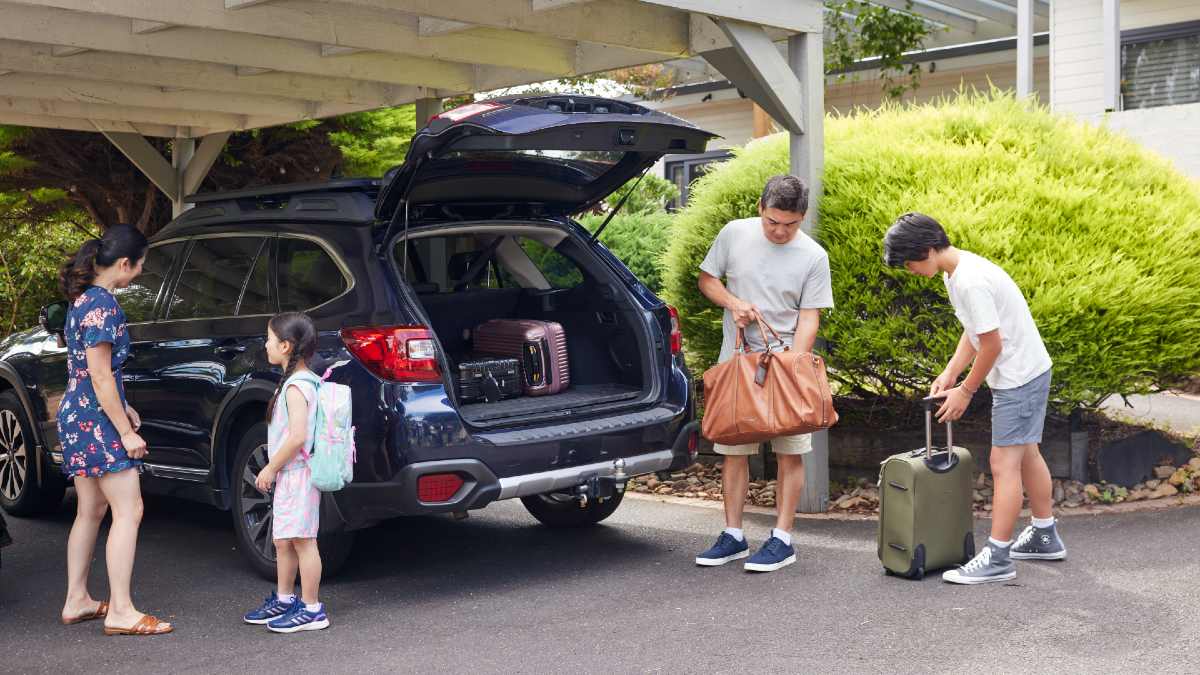 family of four packing luggage into car
