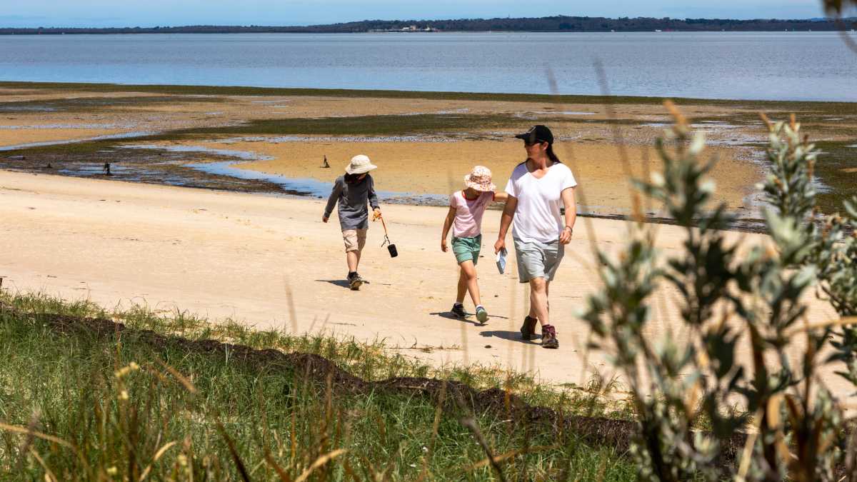 Family walking along sandy beach at low tide.