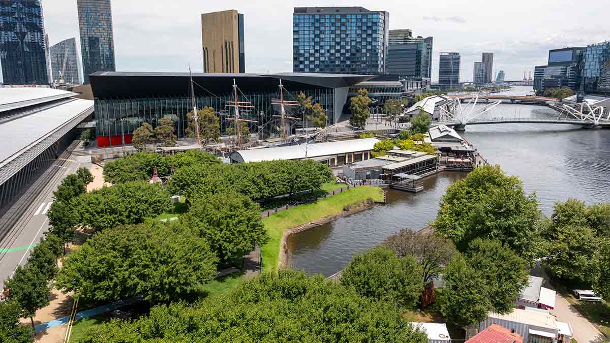 Aerial view of Exhibition Centre with three masts of the historic Polly Woodside ship rising above trees next to Yarra River