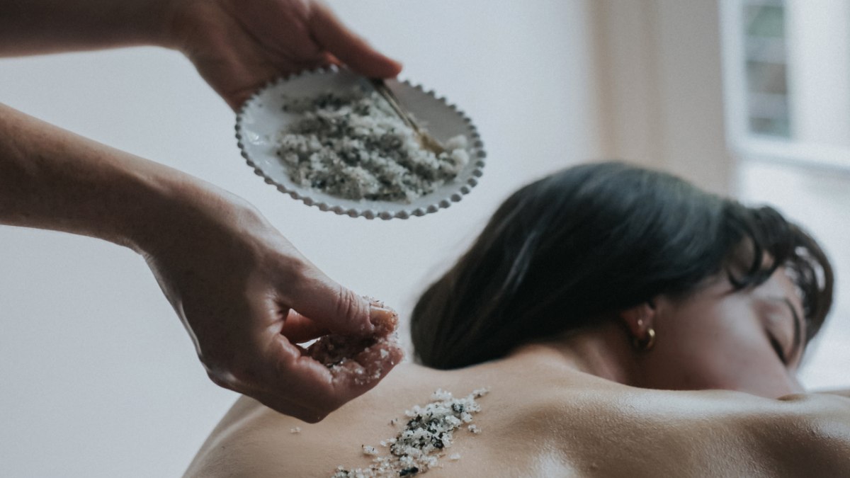 masseuse placing salts on woman's back