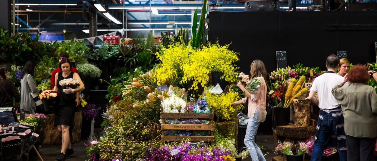 A woman choosing flowers from an overflowing stall at Prahran Market