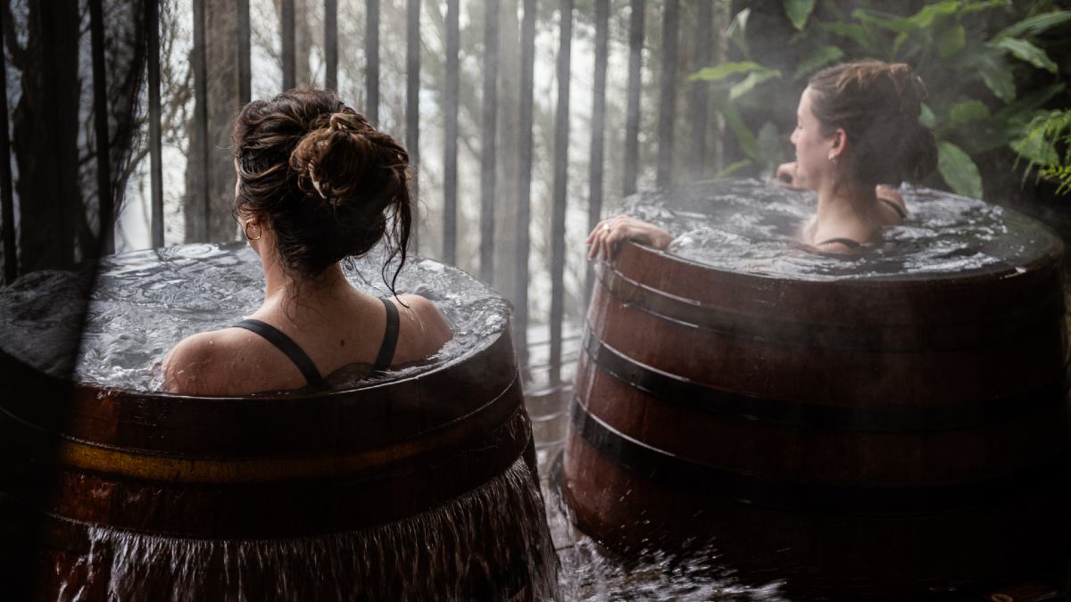 two women bathe in barrels