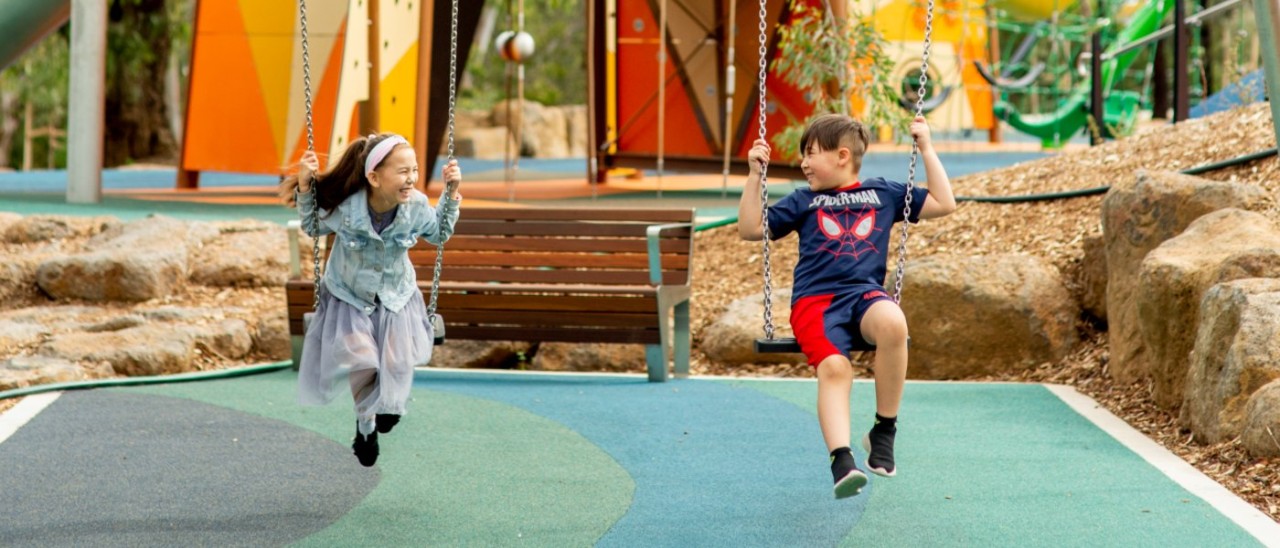 Two children playing on swings at Wyndham Park in Werribee
