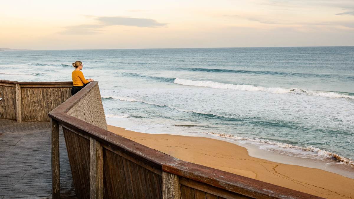 woman watching whales on a boardwalk ocean platform