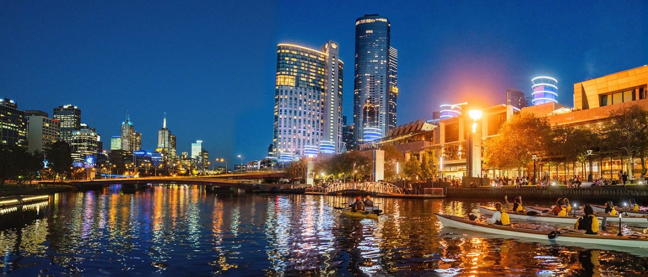 People kayaking on the Yarra River in Melbourne at night.