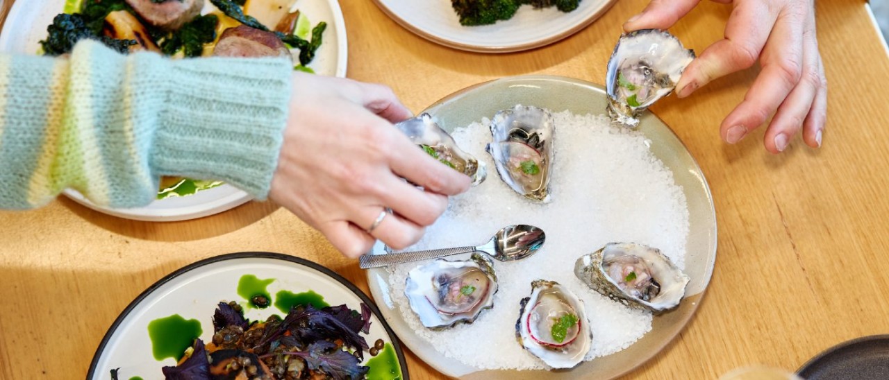 two people eating oysters at a restaurant