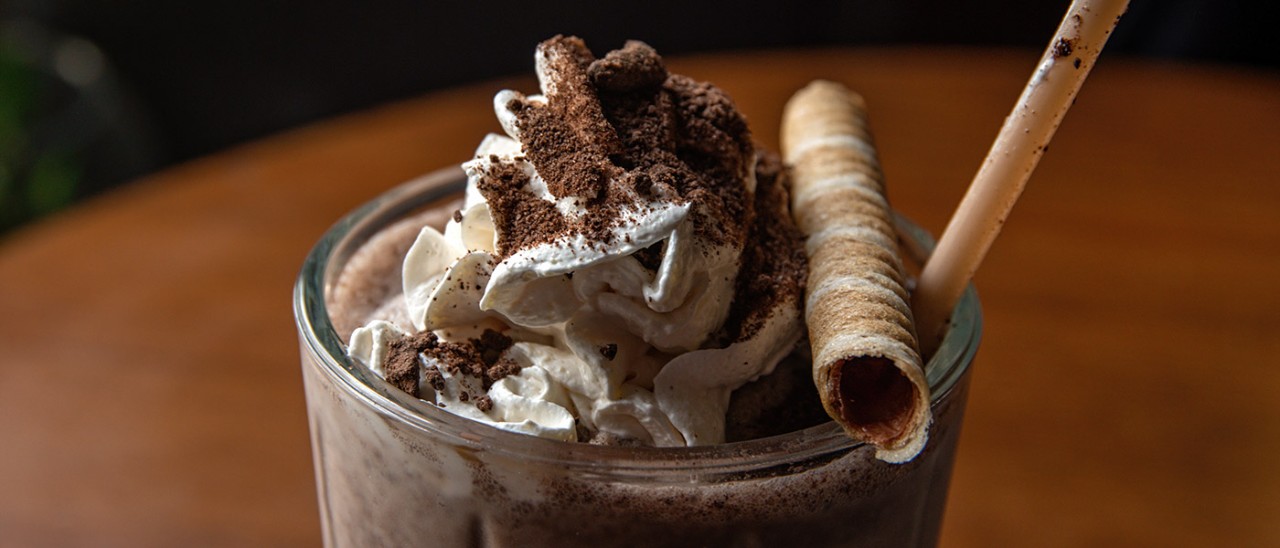 Close-up of chocolate drink with whipped cream and wafer on top.