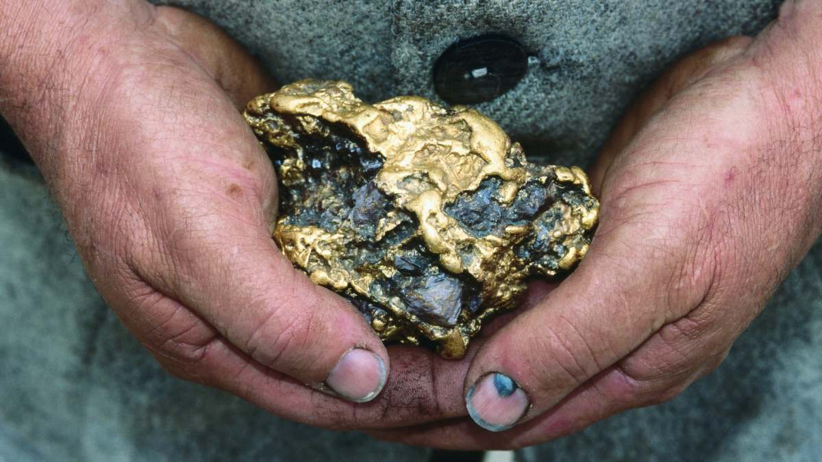 man with dirty hands holding a large gold nugget