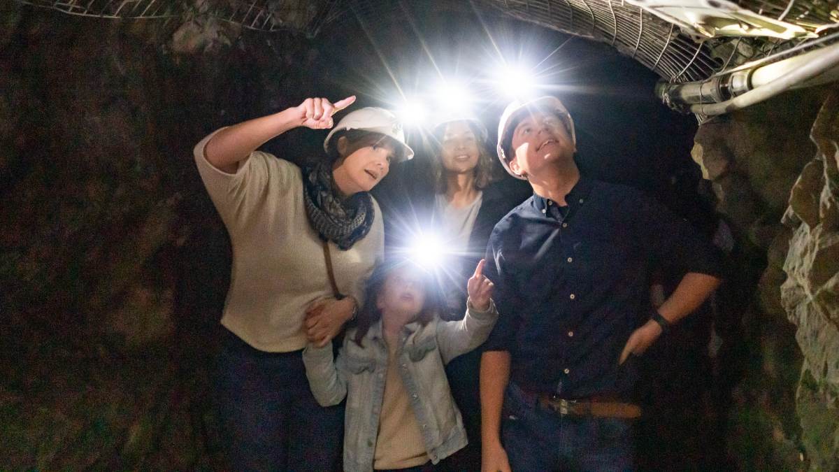 family of four wearing mining helmets in an underground gold mine
