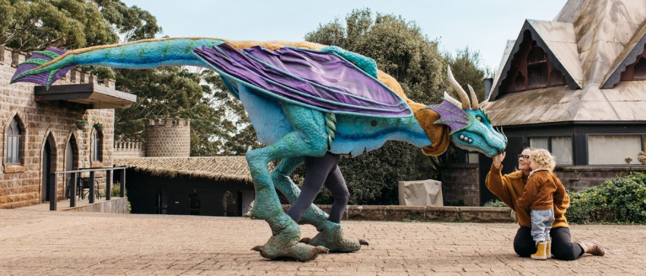 mother and child kneeling and patting a dragon in a medieval castle