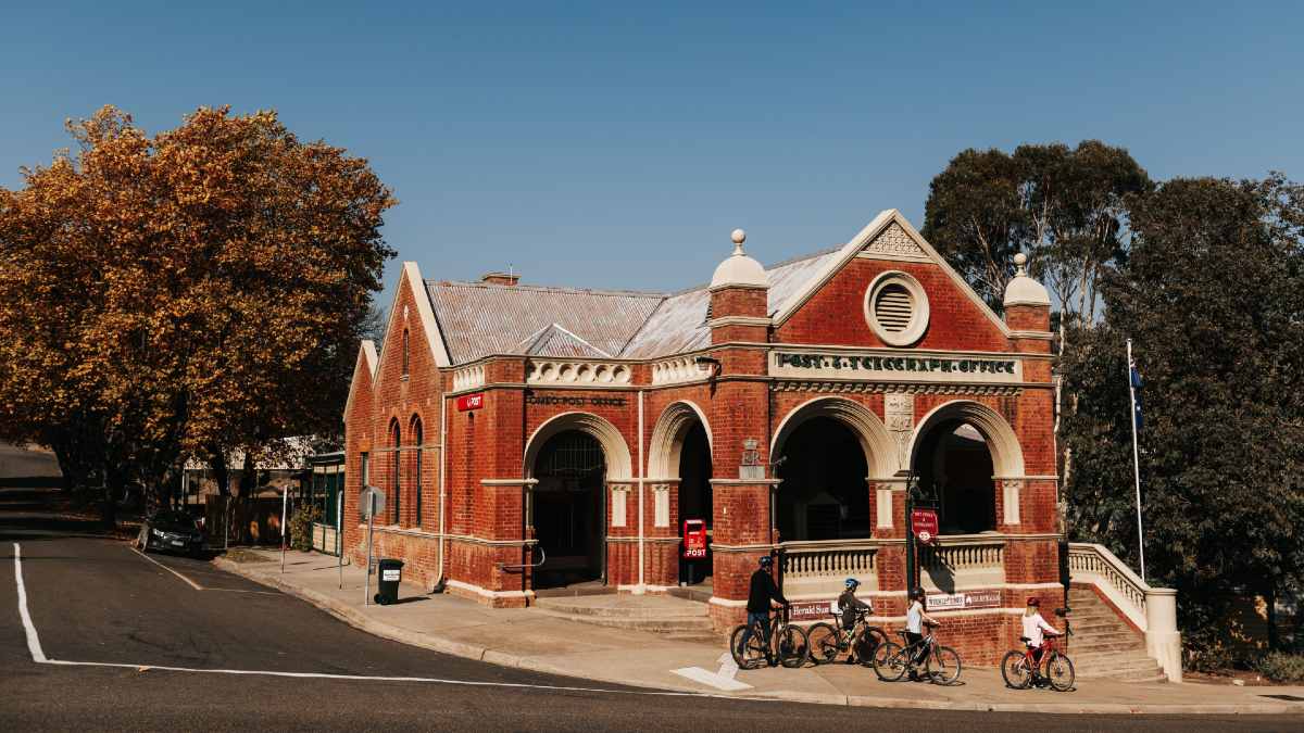 family riding bikes by historic building in Omeo