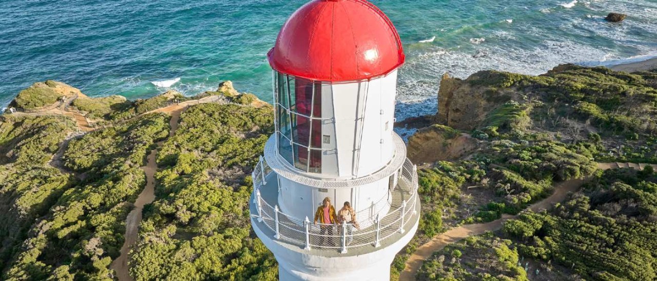 two people standing on observation deck of Split Point Lighthouse with ocean in background