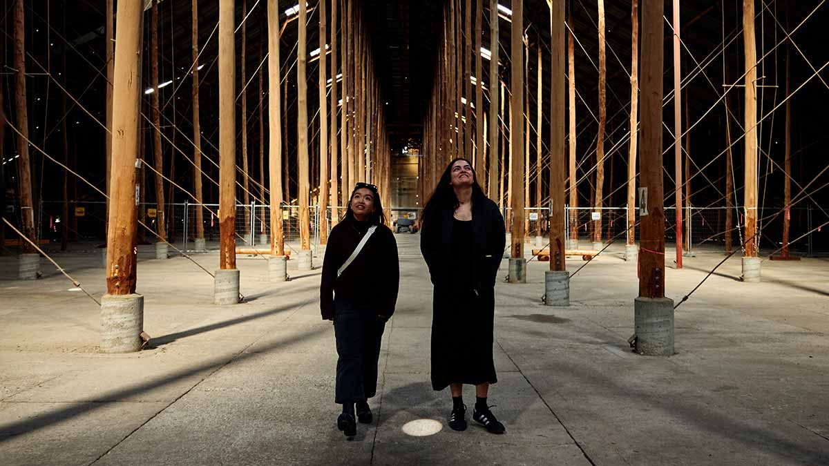 Two women looking up at towering timber poles in a heritage grain shed in Murtoa, Victoria.