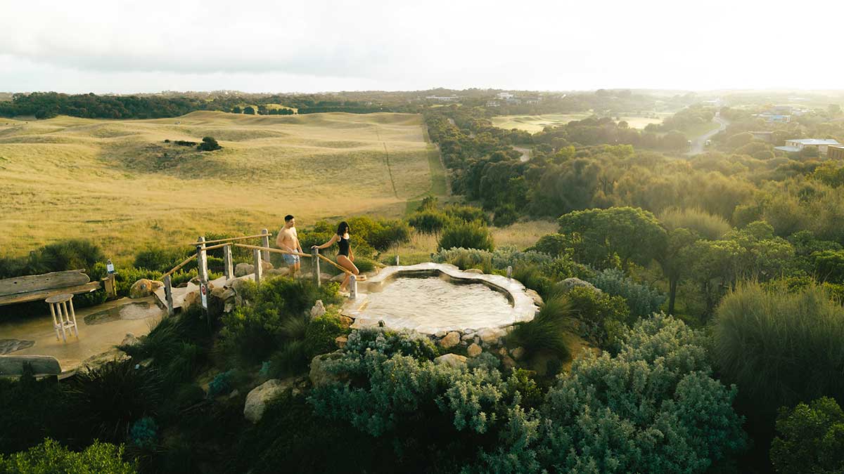 Aerial view of couple getting into pool at top of hill surrounded by farmland on the Mornington Peninsula.