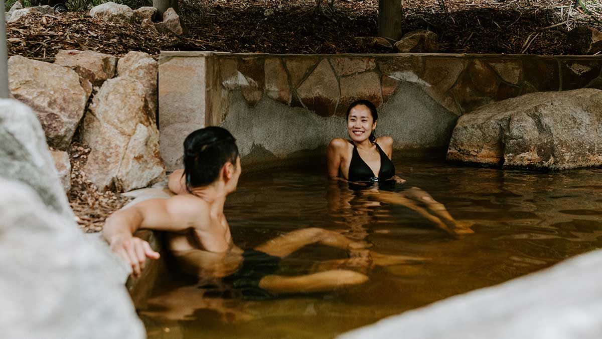 group of people painting clay on their bodies wearing swimsuits