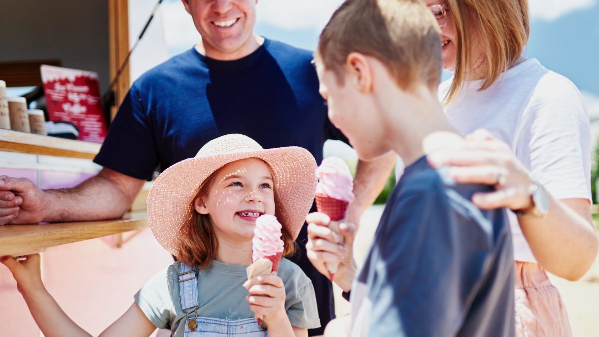 children enjoying cherry ice cream with their parents from an ice cream truck in a cherry orchard