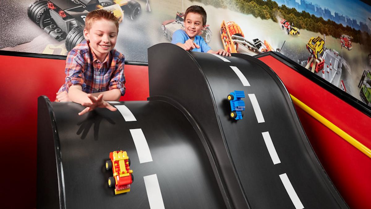 two young boys pushing LEGO cars down a track