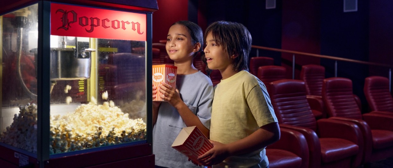 two children getting popcorn in a small cinema