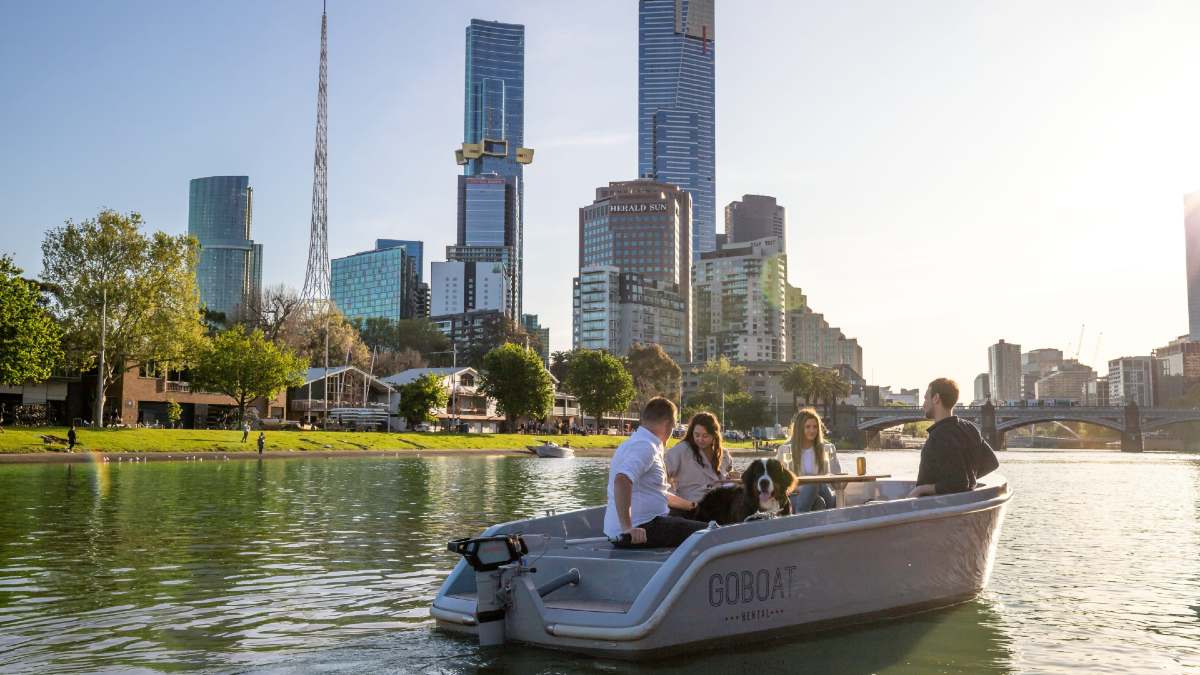 four friends and their dog on a hire board on the Yarra River in Melbourne with city skyline behind