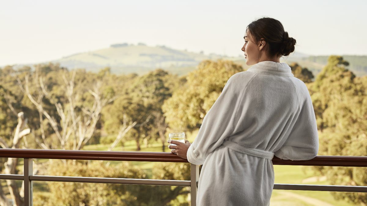 woman dressed in a bathrobe looking at view from balcony