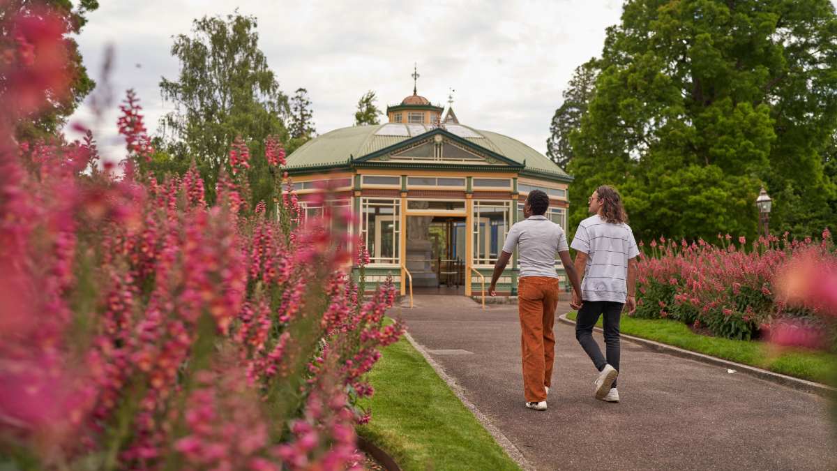young couple walking hand in hand in botanical gardens