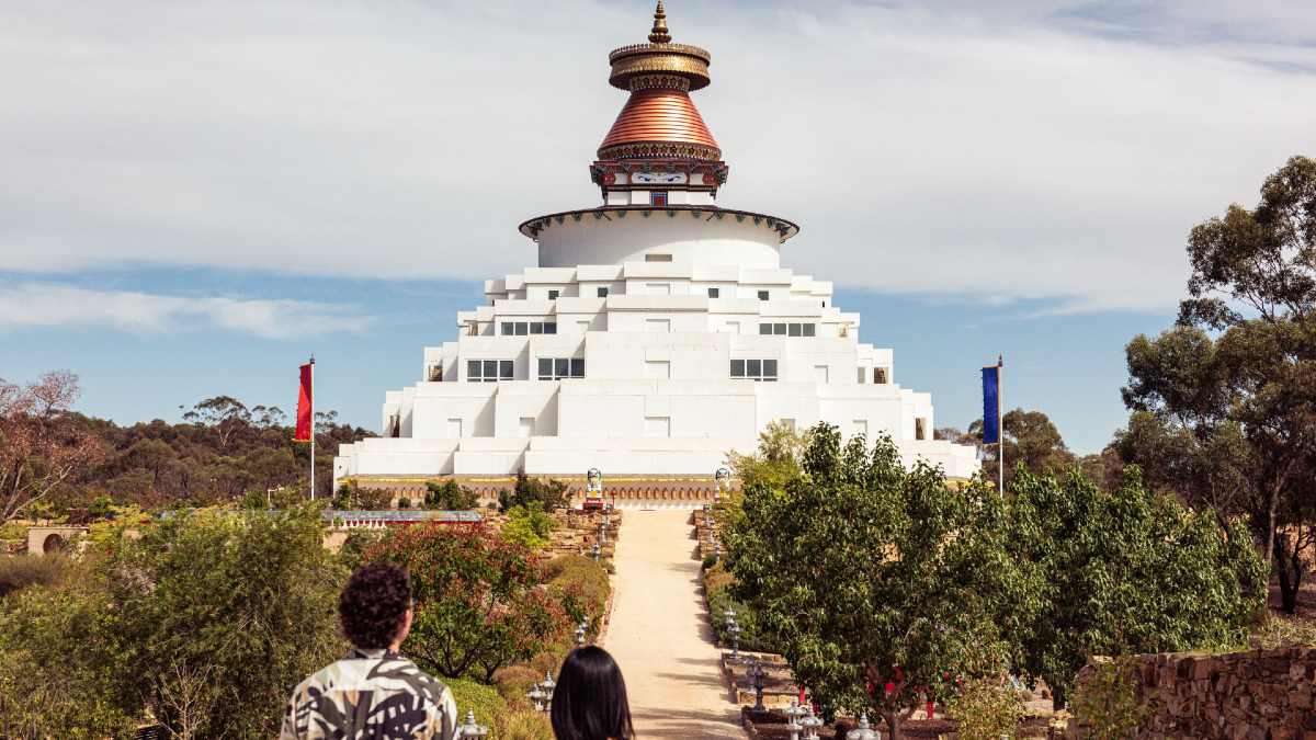 two people looking at large white stupa