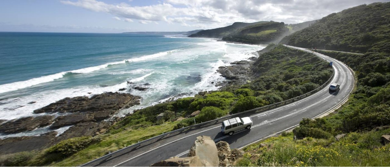 Great Otway National Park_Visit Victoria cars driving on road with ocean on left and rainforest on right