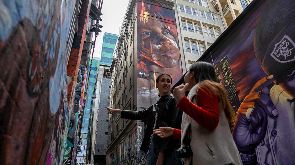 Two women surrounded by street art in a Melbourne laneway.