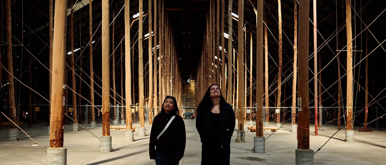 Two women looking up at towering timber poles in a heritage grain shed in Murtoa, Victoria.