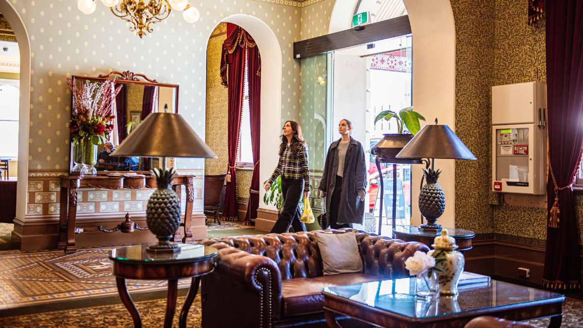 two young women entering an opulent hotel